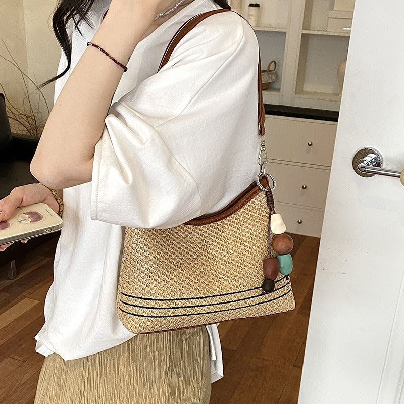 Women's shoulder bag made of woven natural material with decorative pendant