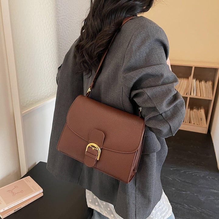 Ladies shoulder bag with elegant flap closure and decorative metal accent